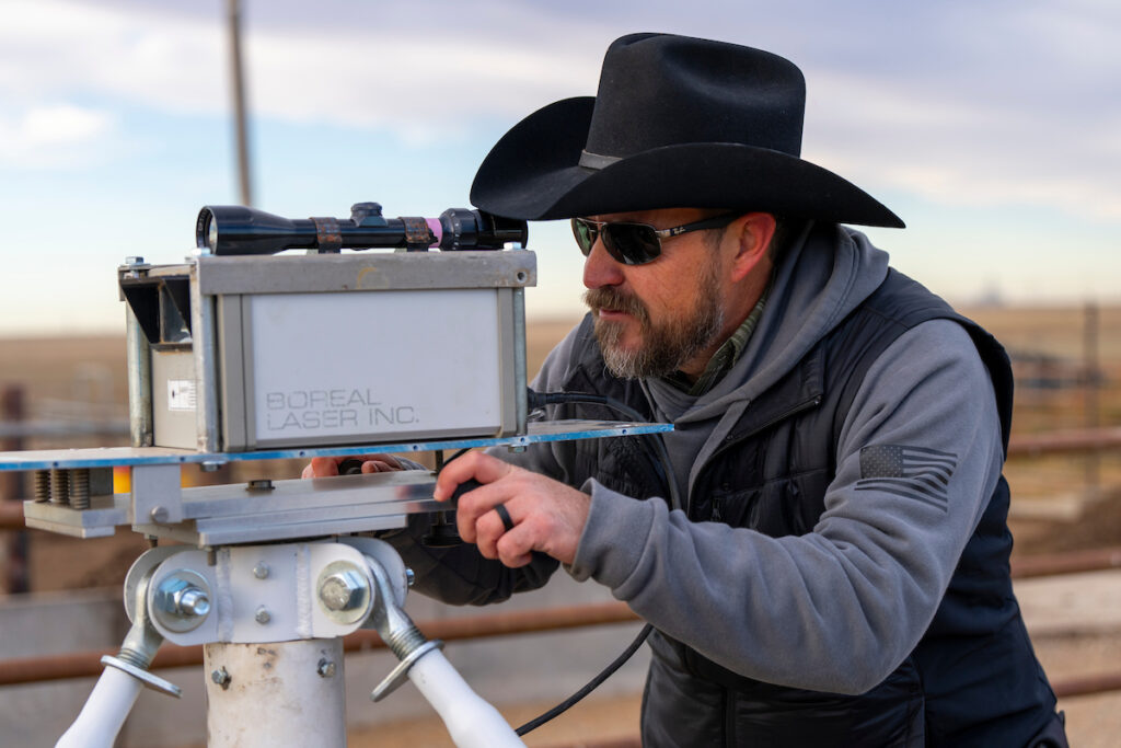 Man looking through scope mounted atop a piece of high-tech equipment on a tri-pod